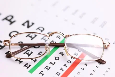 Vision test table and glasses with a colored background. Stock Photos