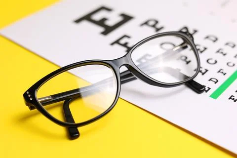 Vision test table and glasses with a colored background. Stock Photos