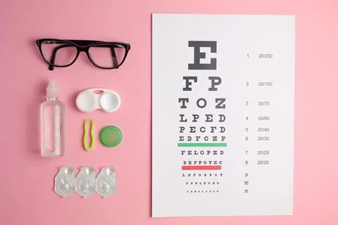 Vision test table, glasses and contact lenses on a colored background. Stock Photos
