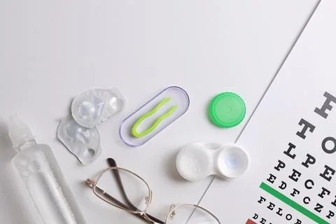 Vision test table, glasses and contact lenses on a white background. Stock Photos