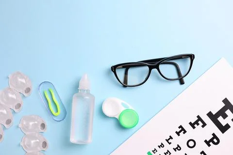 Vision test table, glasses and contact lenses on a colored background. Stock Photos