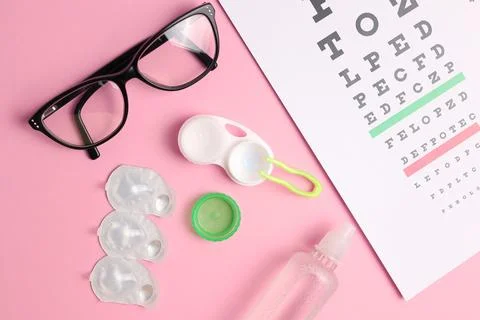 Vision test table, glasses and contact lenses on a colored background. Stock Photos