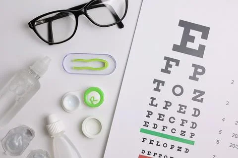 Vision test table, glasses and contact lenses on a white background. Stock Photos