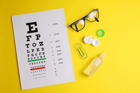 Vision test table, glasses and contact lenses on a colored background. Stock Photos
