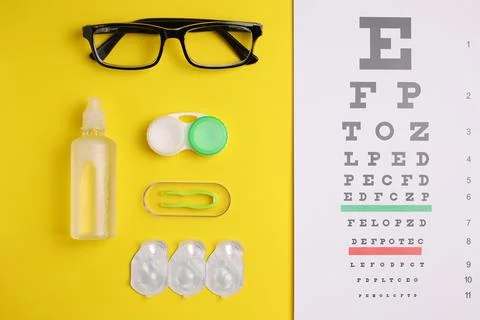 Vision test table, glasses and contact lenses on a colored background. Stock Photos