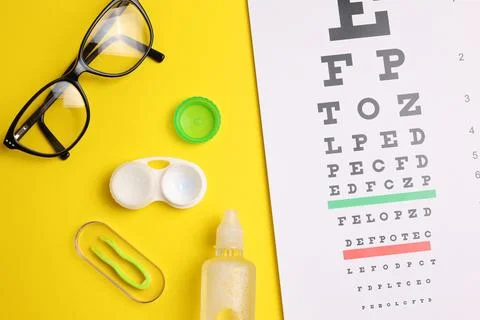 Vision test table, glasses and contact lenses on a colored background. Foto stock