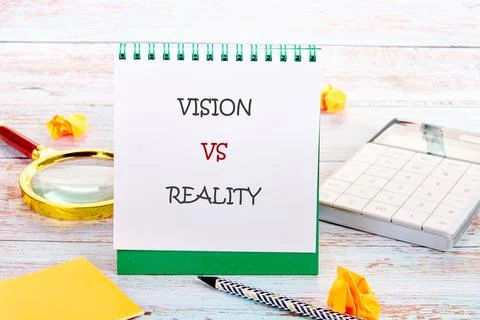 VISION VS REALITY notepad on a desk with magnifying glass, calculator, and .. 스톡 사진