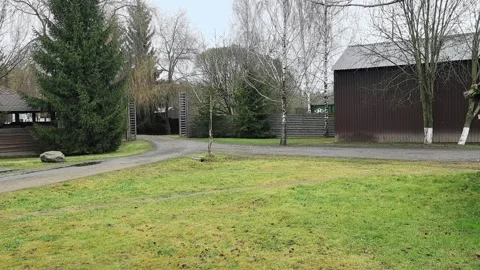 Visit to a quiet farm area with open space, trees, and buildings on a cloudy day Stock-Footage 330188480