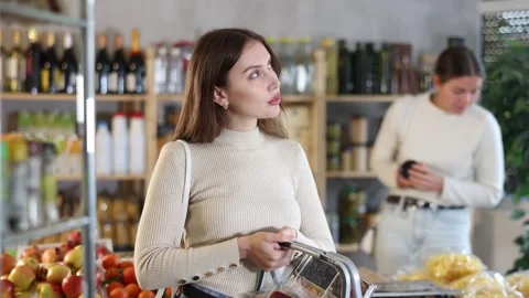 Visiting store woman is looking at something on shelf of showcase, client buy Stock Footage 341532054