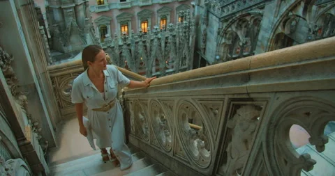 Visitor climbs white marble staircase surrounded by gothic elements at Milan Stock Footage 313697893