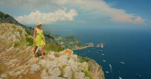 Visitor explores a rocky Capri ridge with sweeping summer views of coastline and Stock Footage 341366920