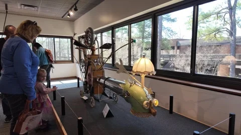 Visitors admire a steampunk machine in a museum Stock Footage 345618955