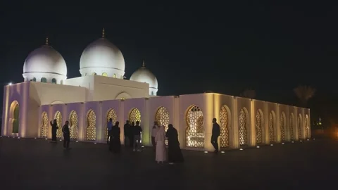 Visitors admiring lit facade of at Sheikh Zayed Grand Mosque at night Stock Footage 339765839