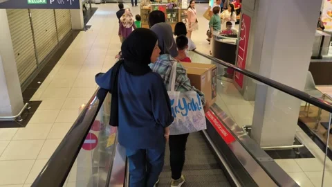 Visitors of all ages traverse the escalators inside Lotus Mall in Teluk Intan Stock Footage 301441562