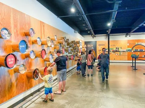 Visitors and children interacting with a large wooden wall display inside a.. Fotos Stock