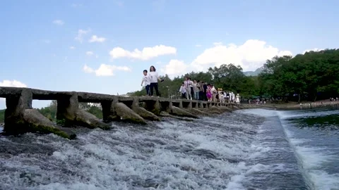 Visitors cross the stone bridge over the river Stock Footage 191282345