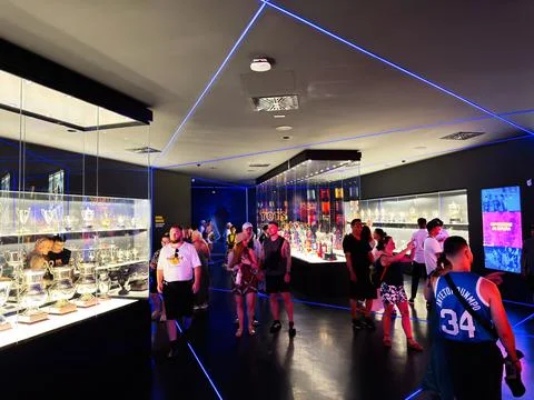 Visitors exploring a modern trophy room full of shining cups and memorabili.. Stock Photos