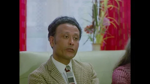 Visitors interviewing young sitting indian boy, when older son arrives, 1971 Stock Footage 133380992