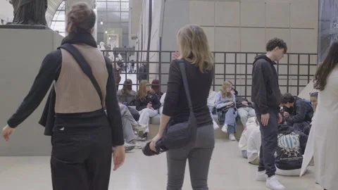 Visitors at the Musée d'Orsay sitting and browsing on their smartphones in the Stock Footage 305473578
