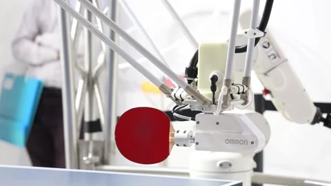 Visitors playing ping-pong table tennis with robot Forpheus on Omron stand on Stock Footage 97789529