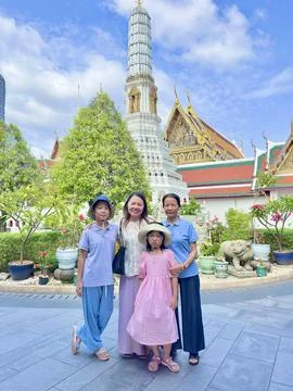 Visitors posing beside ancient stone statues and white pagodas within the Foto stock