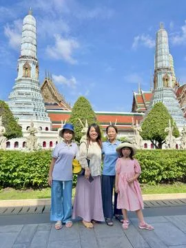 Visitors posing beside ancient stone statues and white pagodas within the Stock Photos