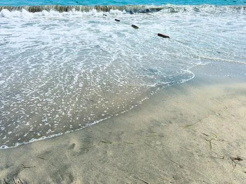Visitors see waves breaking on the beach while wooden logs lie on the sand. T Stock Photos