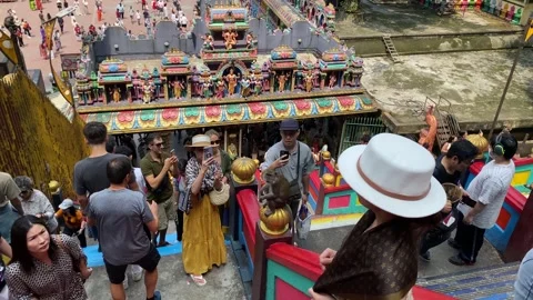 Visitors take pictures next to a monkey in Batu Caves, Kuala Lumpur, Malaysia 4K Stock Footage 247620113