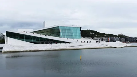 Visitors walk across sloping white marble roof oslo opera house angular lines Video stock 327632646