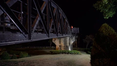 Visitors walk along the Bridge on the River Kwai at night. Video stock 74294652