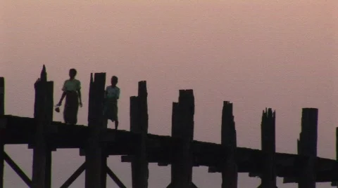 Visitors walking across U Bein’s Bridge at sunset in Amarapura, Burma Stock Footage 475702