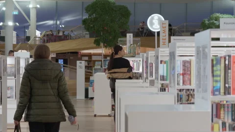 Visitors walking between bookshelves inside Helsinki Oodi Central Library Stock Footage 326637236