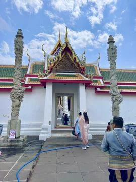 Visitors walking through a small gate decorated with intricate gold patterns Foto stock