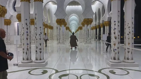 Visitors walking through stunning marble colonnade of Sheikh Zayed Mosque at Stock Footage 339765778