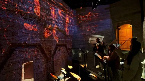 Visitors watch immersive projection mapping across medieval brick walls inside Stock Footage 326327689