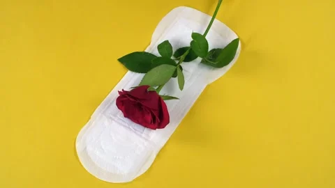 A visual shot of a white sanitary pad with a red rose over it on yellow backg... Stock Footage 264025886