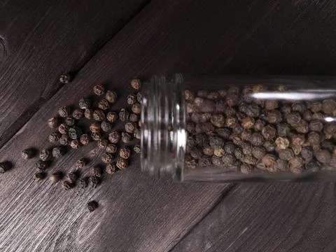 A visually appealing image depicting spilled peppercorns from a glass jar Stock Photos