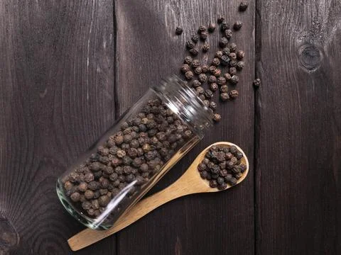 A visually appealing image depicting spilled peppercorns from a glass jar Stock Photos