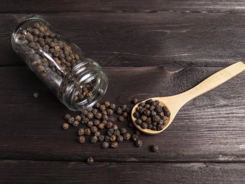 A visually appealing image depicting spilled peppercorns from a glass jar Stock Photos