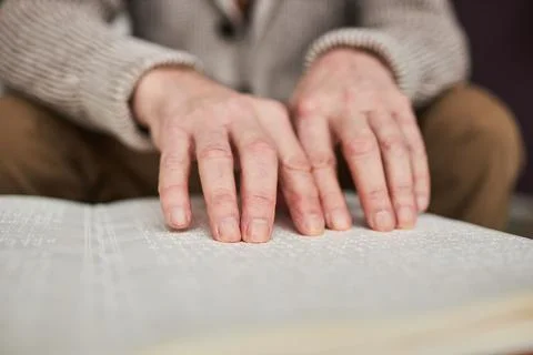 Visually impaired man reading book in Braille Stock Photos