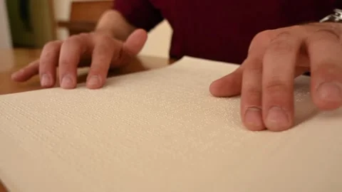 Visually impaired man reading a braille book. Stockbeeldmateriaal 202116728