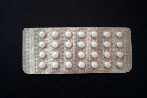 A visually striking blister pack of white pills placed on a black background Stock Photos