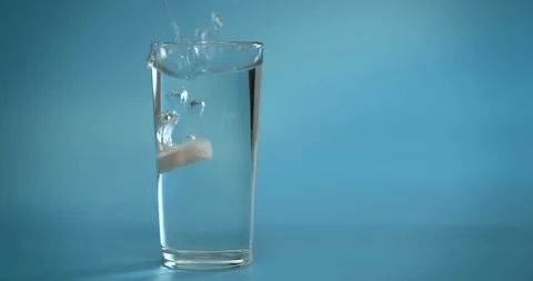 A vitamin C tablet is thrown into a transparent glass glass with water. The Stock Footage 126103108