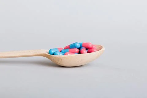 Vitamin capsules in a spoon on a colored background. Pills served as a health Stock Photos