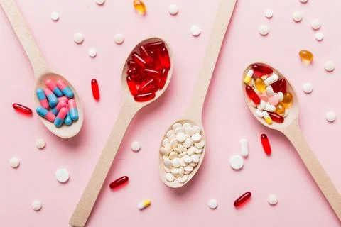 Vitamin capsules in a spoon on a colored background. Pills served as a heal.. Stock Photos