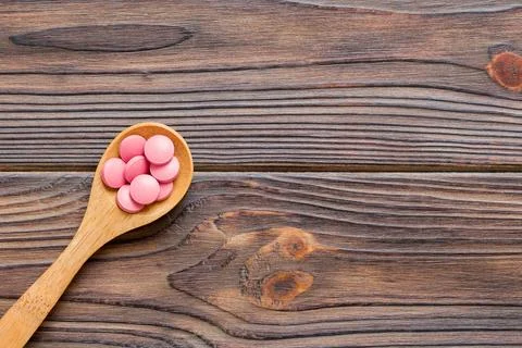 Vitamin capsules in a spoon on a colored background. Pills served as a heal.. Stock Photos