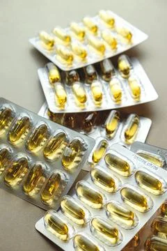 Vitamin capsules spread across a soft brown surface in vibrant golden hues Stock Photos