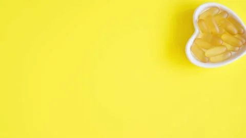 Vitamin D and Omega 3 fish oil capsules supplement in a heart-shaped plate on Stock Footage 155133699