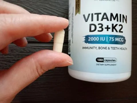 A vitamin D capsule between a woman's fingers Stock Photos