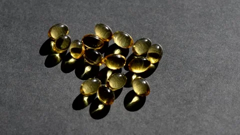 Vitamin D capsules pour on top. black background. Biologically active additives Stock Footage 149402087